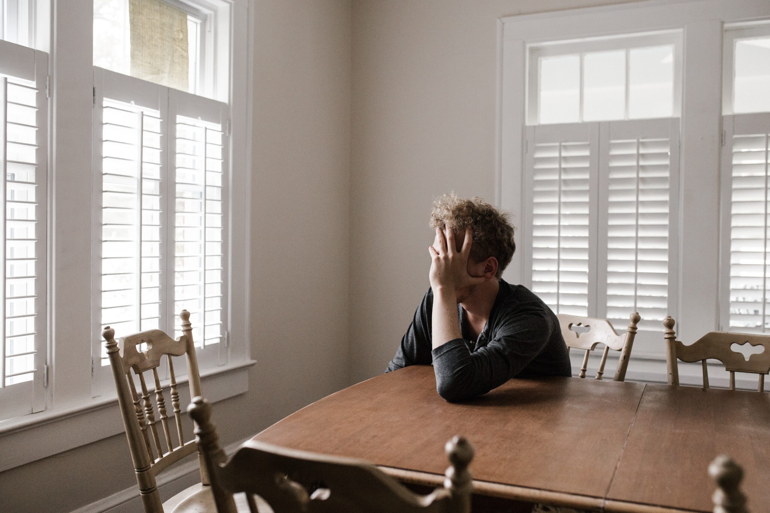 man-leaning-on-wooden-table