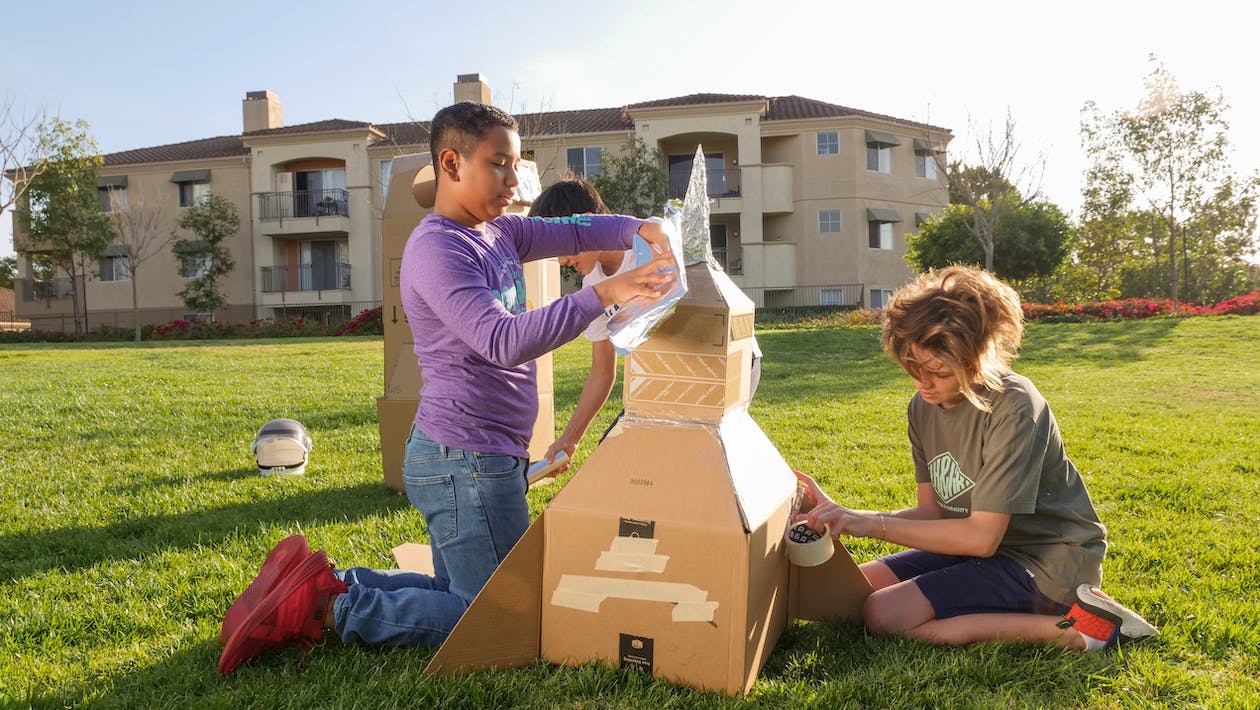 Children making cardboard rocket outside