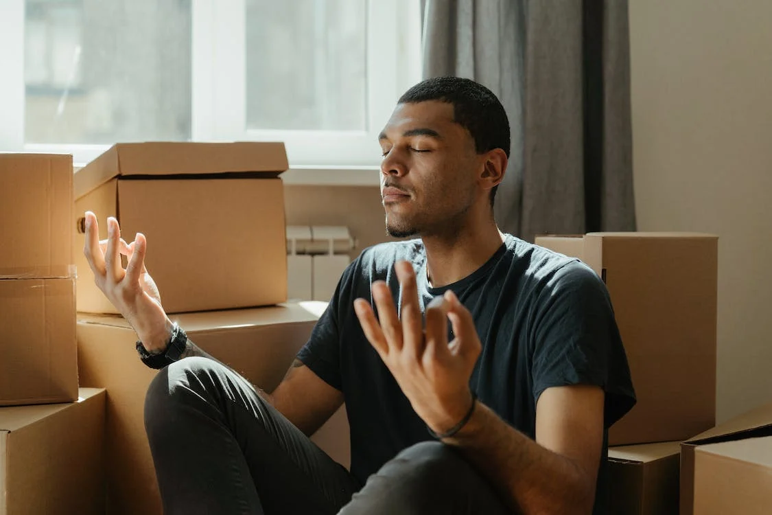 Man trying to meditate in a room full of boxes