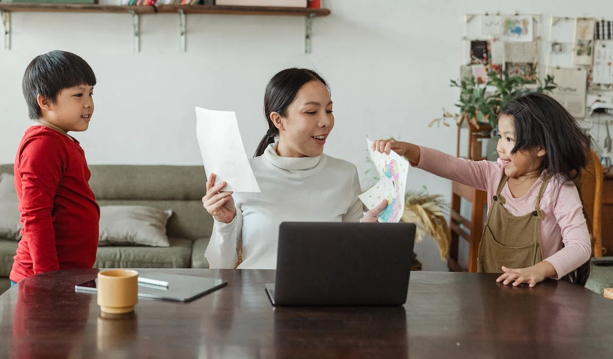 Working mother happily looking at kids’ drawings