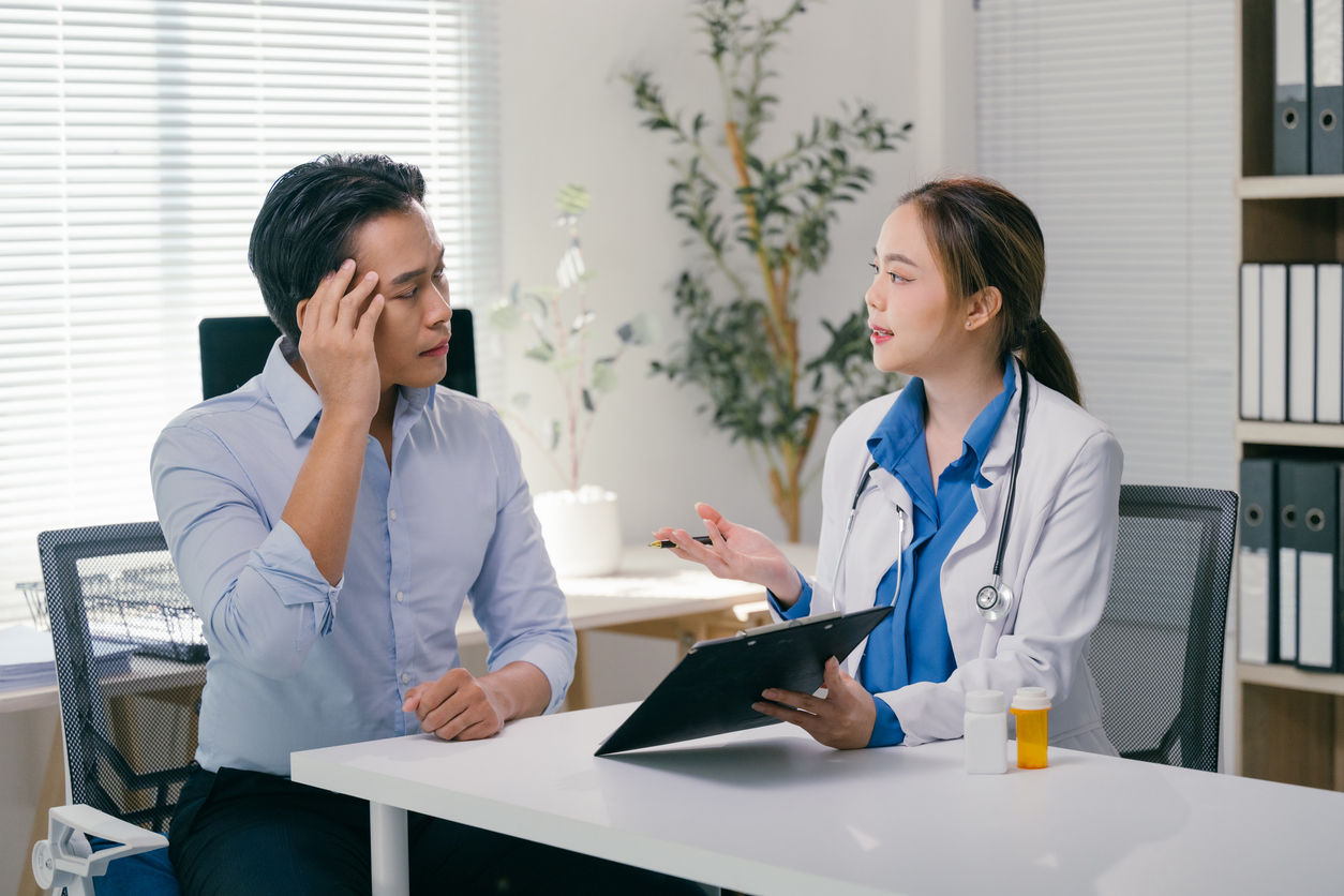 Female doctor holding clipboard listening to patient complaints about headache