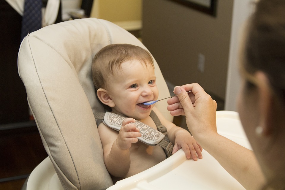 A smiling baby while his mother feeds him