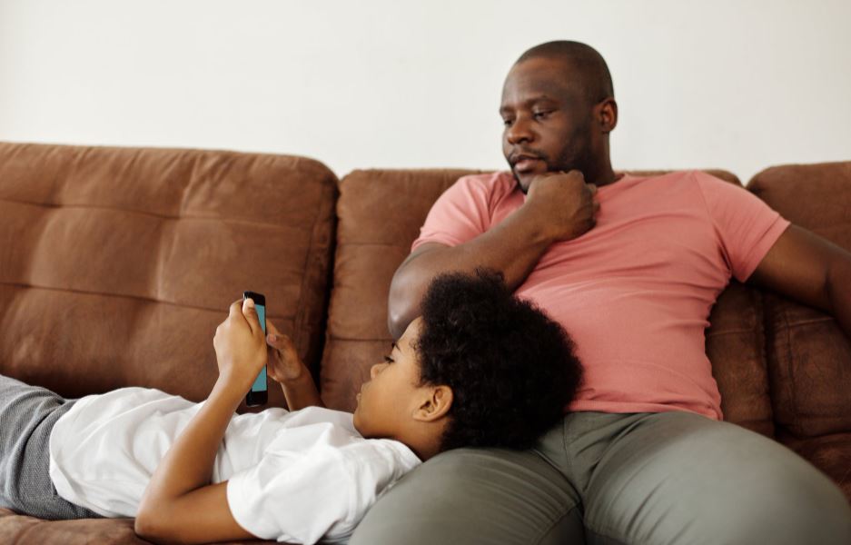 father-looking-at-his-son-playing-on-a-smartphone