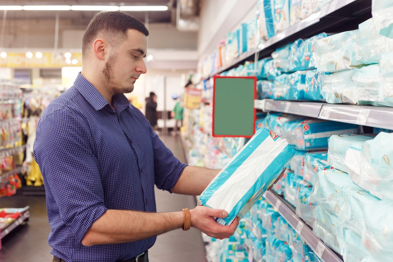 man with diaper pack in supermarket reading product information