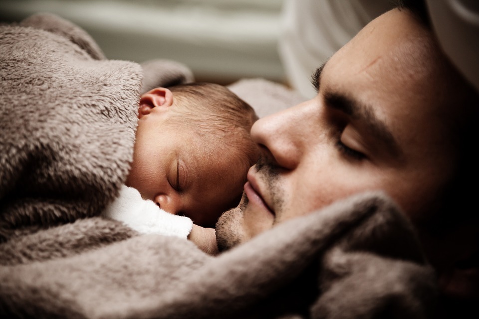 A baby sleeping on his father’s chest