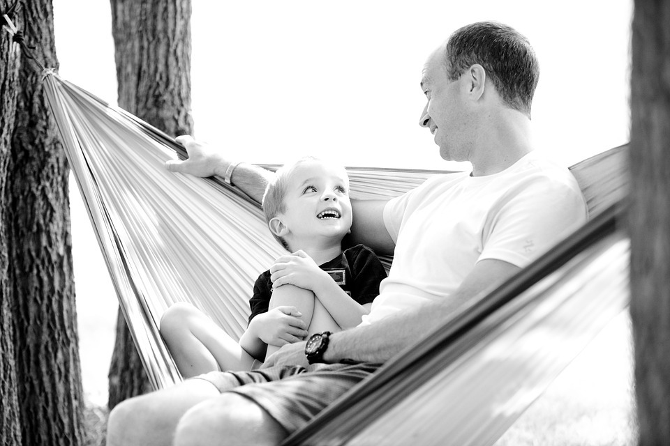 A father and son, talking to each other in a hammock