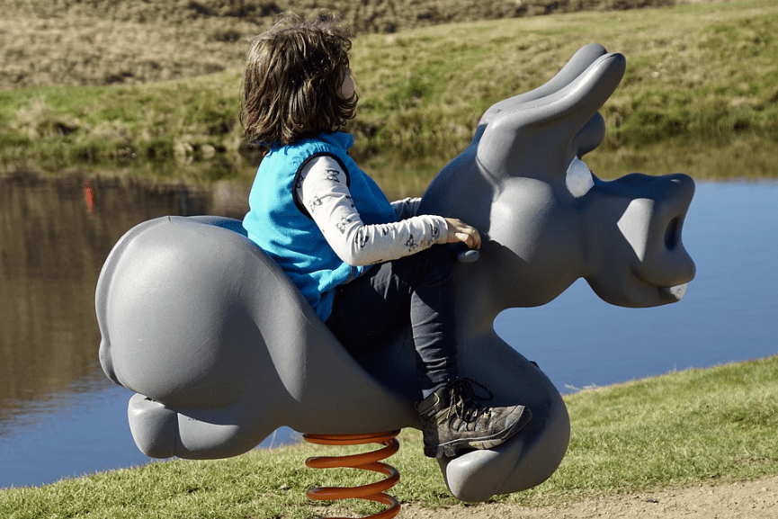 a child riding on an artificial donkey 