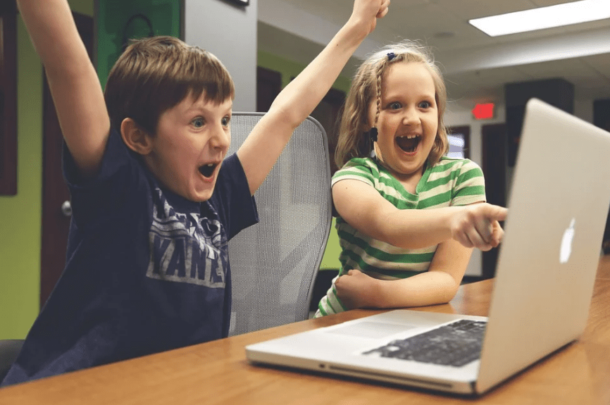 boy and girl cheering, laptop, table, chair, house interior