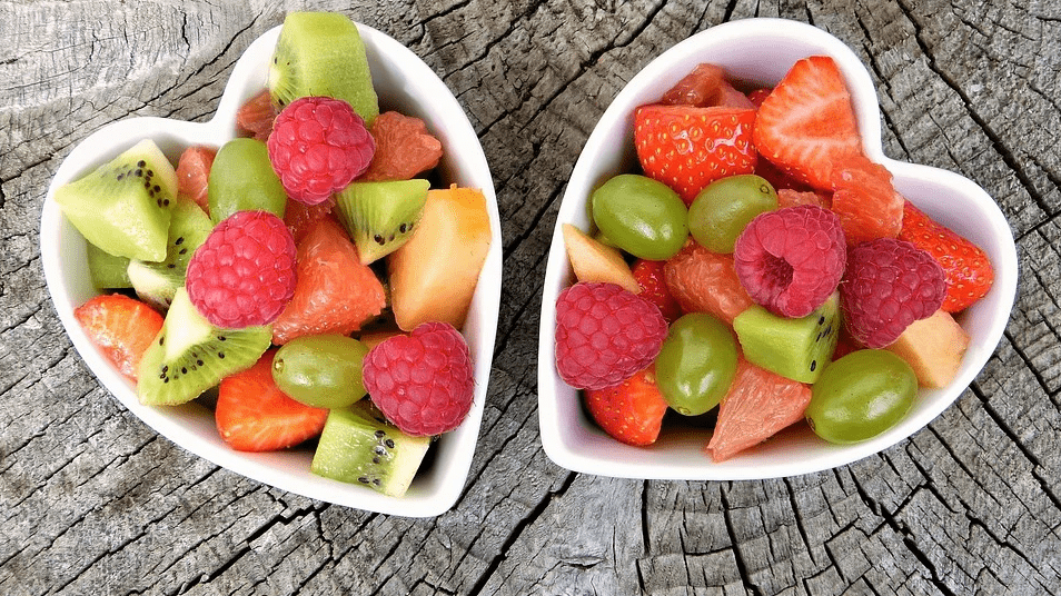 sliced fruits inside two heart-shaped bowls