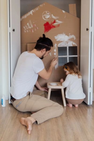 man-in-white-t-shirt-and-brown-pants-painting-cardboard-house