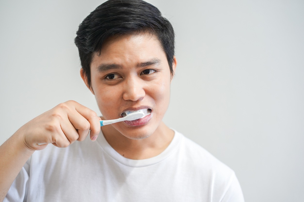 close up young asian man using toothbrush for brushing teeth at bathroom in the morning daily , lifestyle healthcare concept