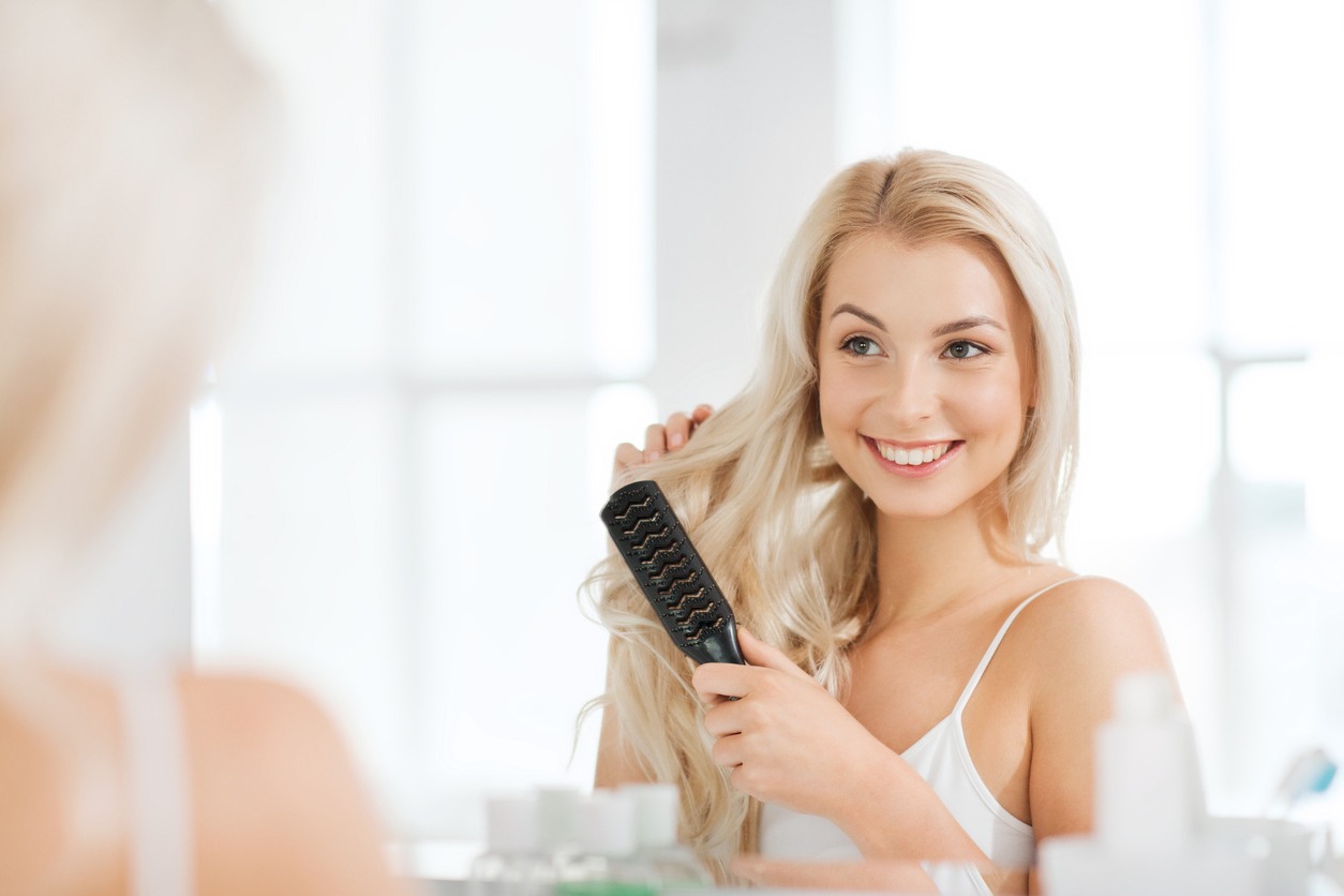 happy woman brushing hair with comb at bathroom