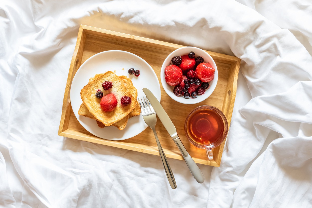Beautiful bright breakfast in bed on a sunny morning. Toast with berries and a cup of tea on a tray. Concept of tranquility, calm, weekend, for mom, for the beloved woman, breakfast at the hotel