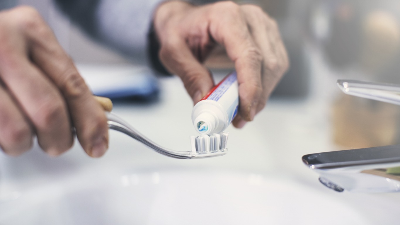 Hand extrude a toothpaste from a tube on a toothbrush