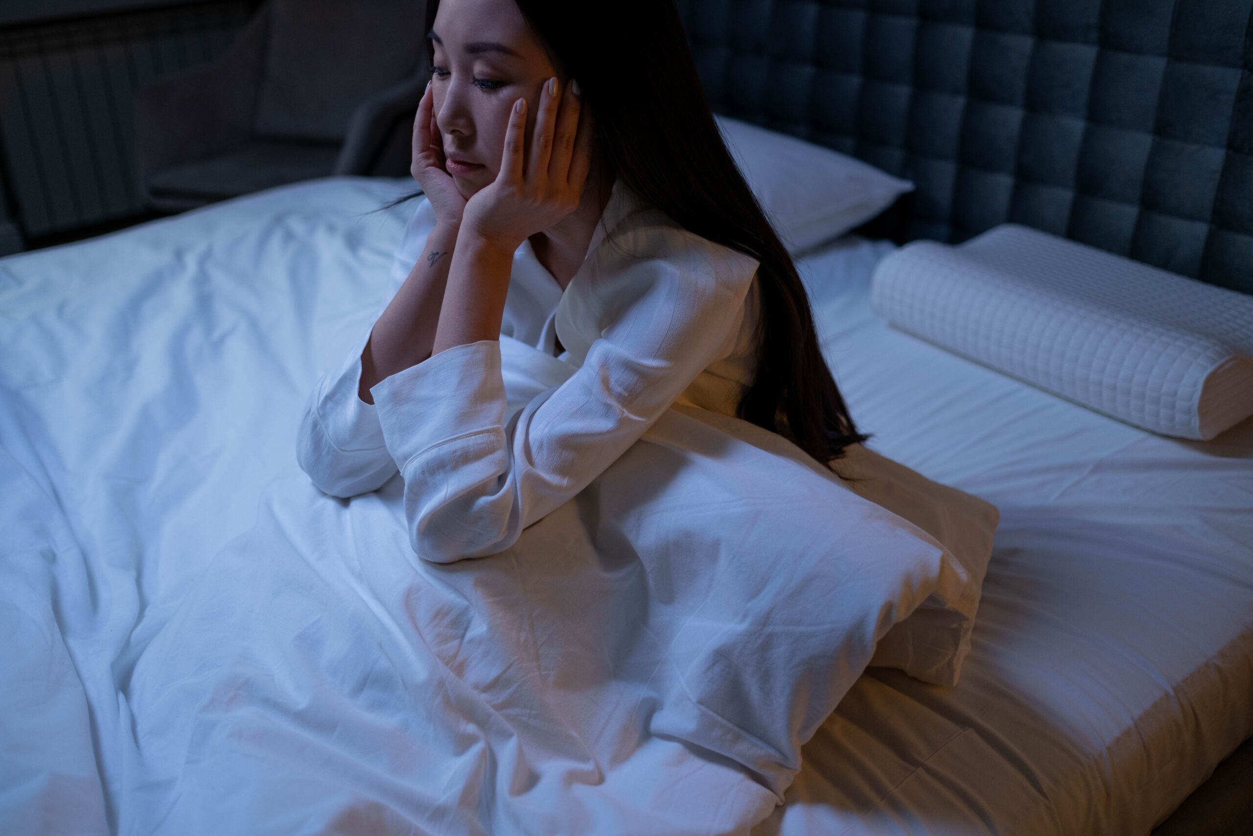 woman-in-white-long-sleeve-shirt-sitting-on-a-bed