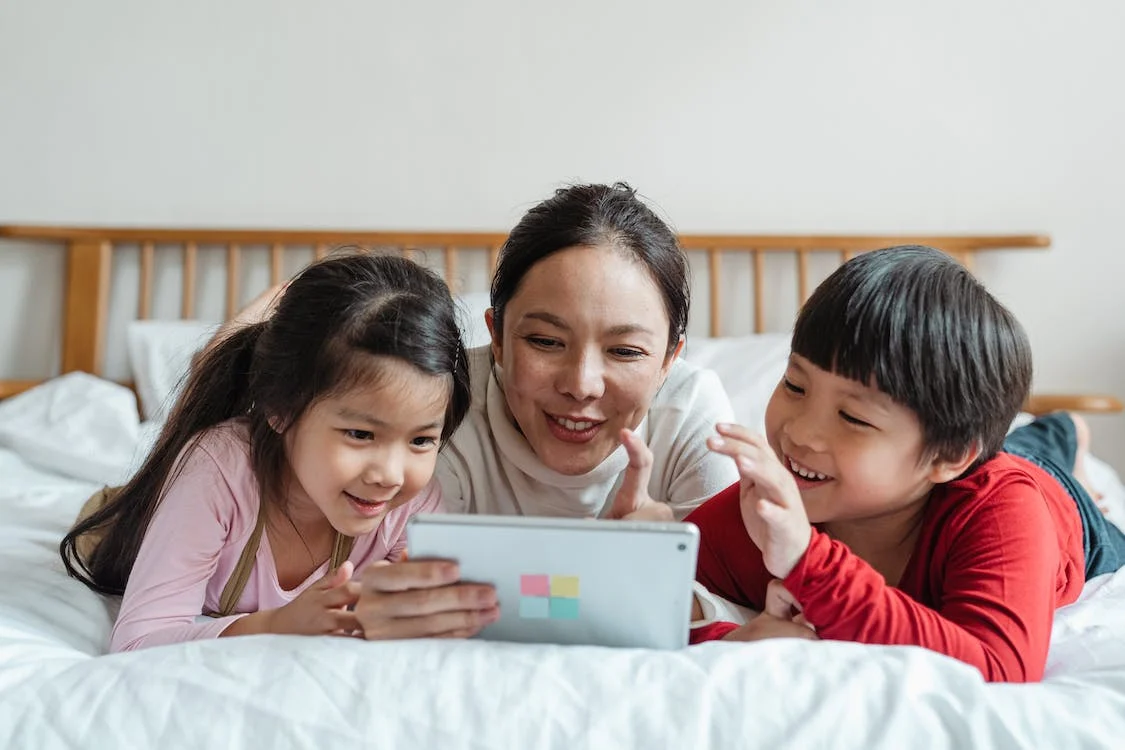 Mother sharing tablet with children