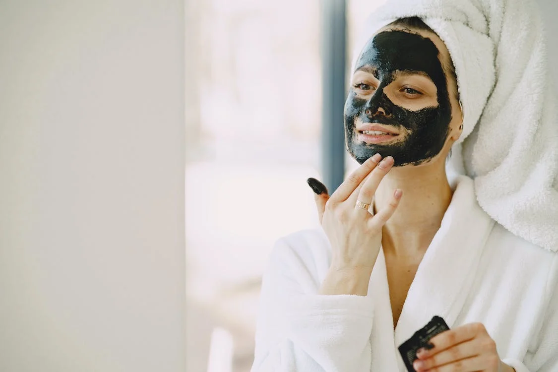 Woman applying clay mask on her face